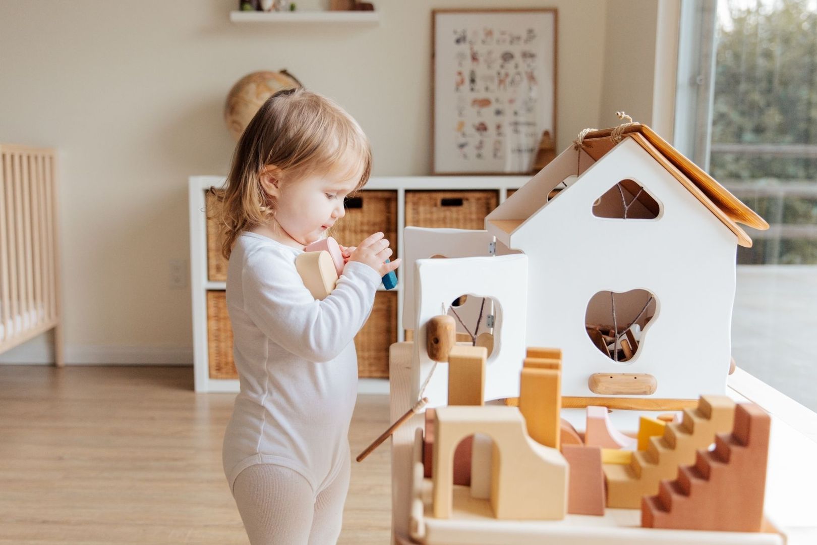 Barn leker självständigt med ett trähus och träleksaker i hemmet